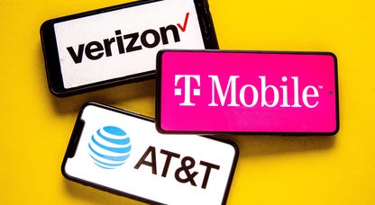 Three smartphones, each showing the name and logo of either Verizon, T-Mobile or AT&T