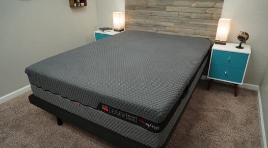 Mattress on a bed frame with a wooden panel behind it