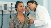 Woman sitting in a doctor's office having her ears checked.