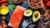 A plate of salmon, avocado, spinach and nuts