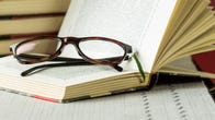 Pair of reading glasses resting in an open book.