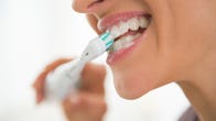 Closeup of a person brushing their teeth with an electric toothbrush
