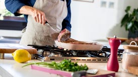 Person preparing grilled steak at home