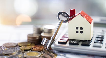 A keychain house on top of a calculator next to coins