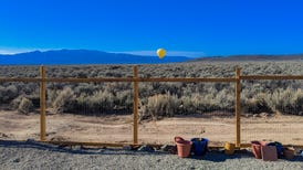 A yellow hot air balloon over a sage brush-covered landscape.