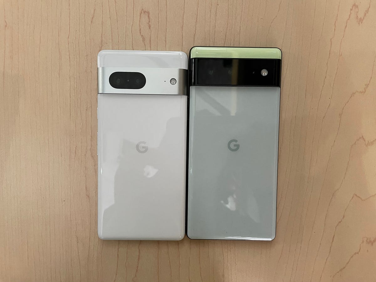 Google's Pixel 7 (next) left to the Pixel 6 (right) on a wooden background