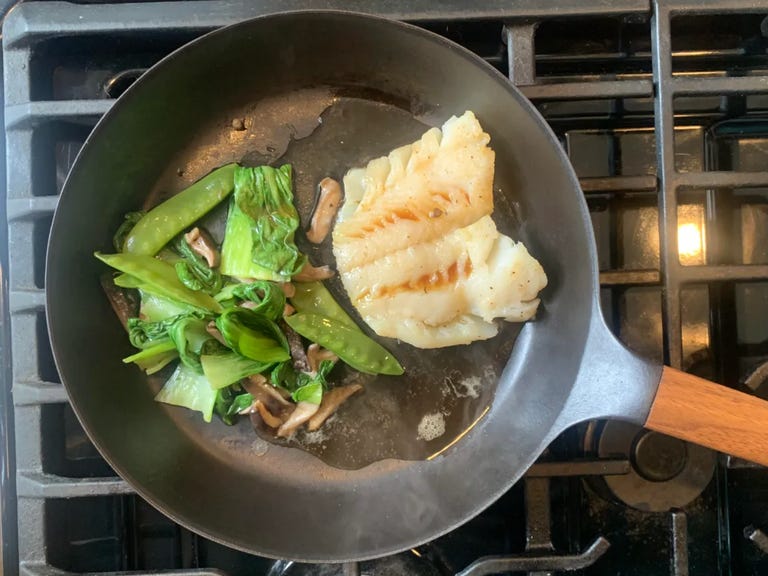 fish and veggies being heated in pan